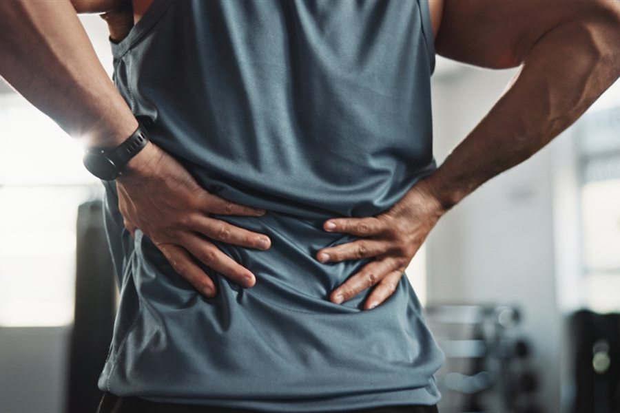 A man in a gym holding his lower back in pain