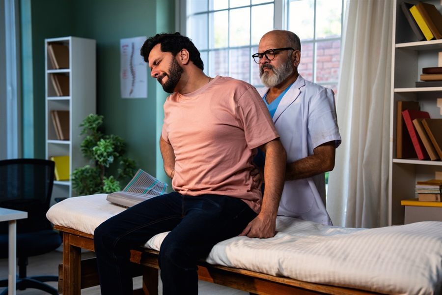 A clinician examining a patient's back during a physiotherapy assessment
